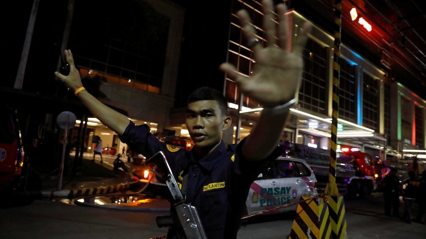 A security guard holds his arms in the air to stop photographers from entering the vicinity