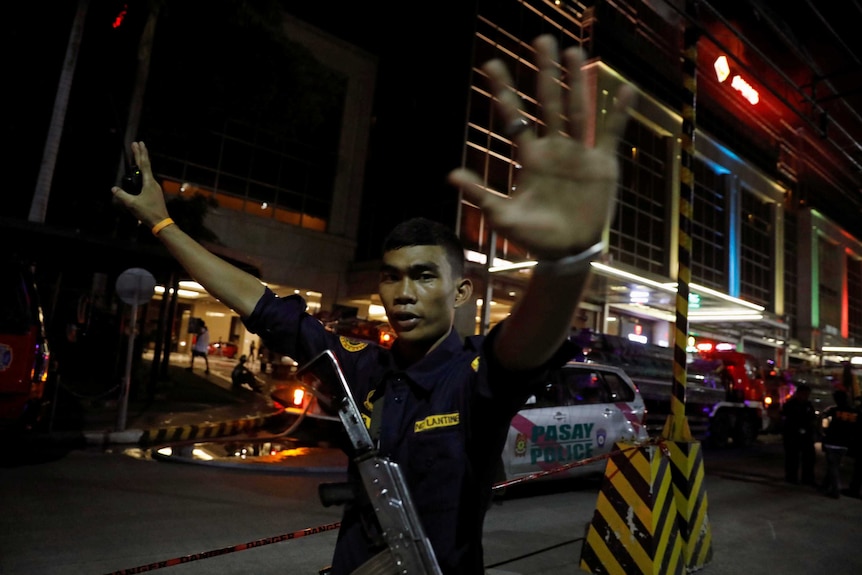 A security guard holds his arms in the air to stop photographers from entering the vicinity