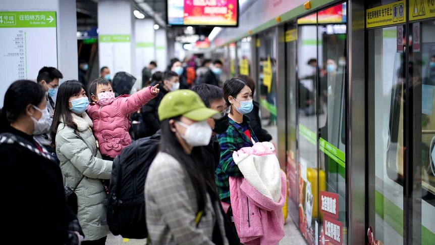 People wear masks while waiting for a train in China.