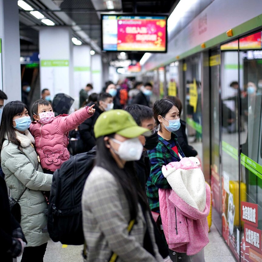 People wear masks while waiting for a train in China.