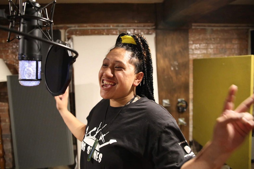 A young woman singing in front of a studio microphone