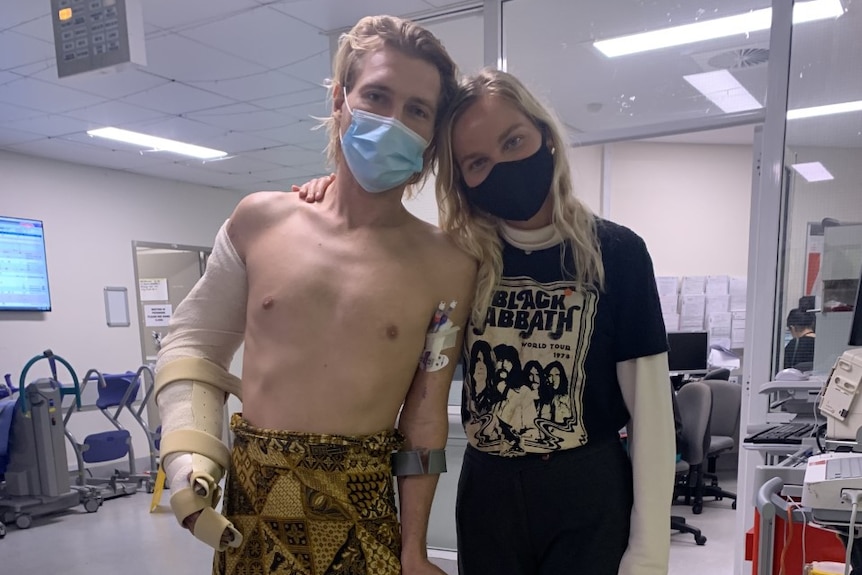 Man standing in hospital with bandaged arm and girlfriend 