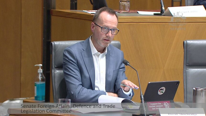 A man in a suite at a parliamentary inquiry speaks into a microphone.