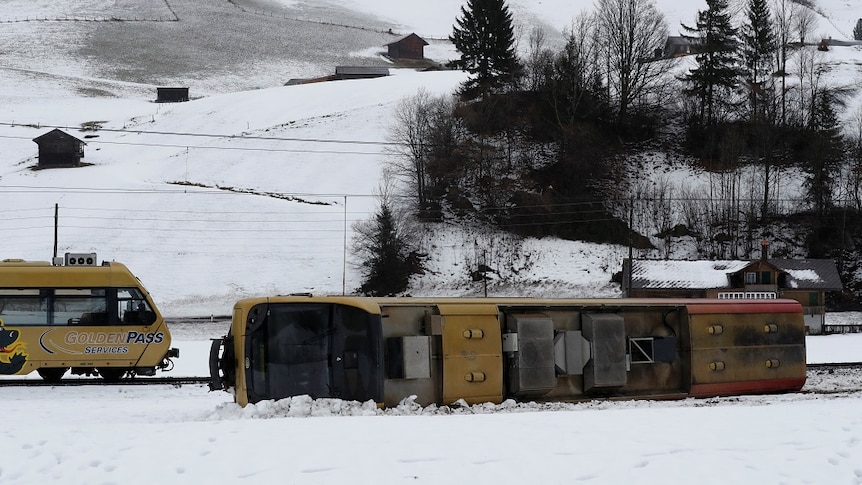 A train carriage lies on its side in the snow.