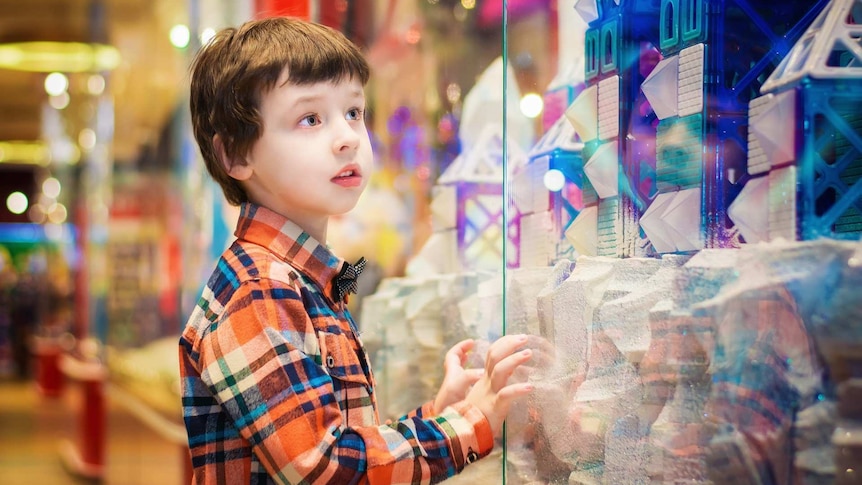 A boy peers into a toy display.