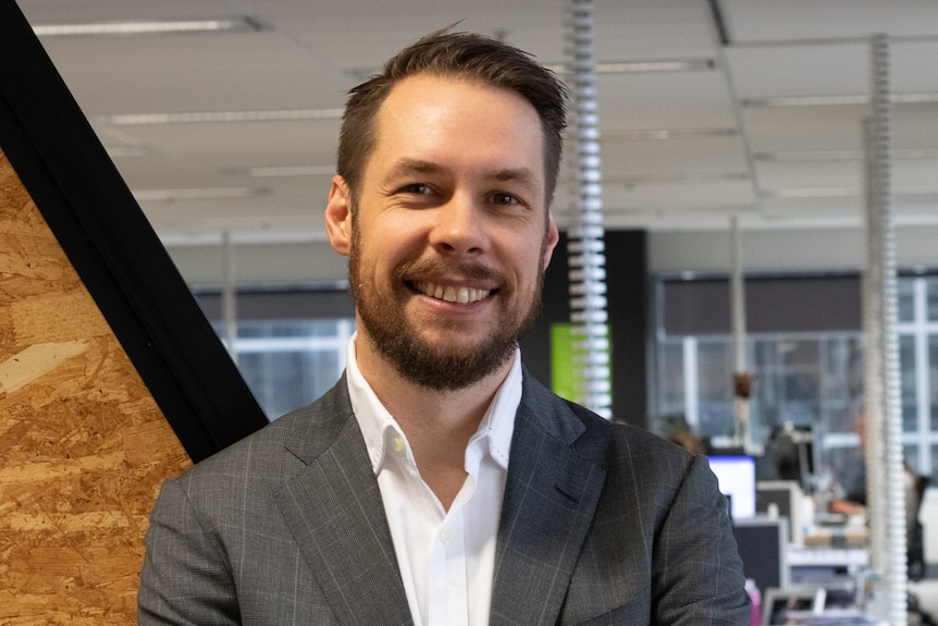 a man ina suit folding his arms smiling into the camera