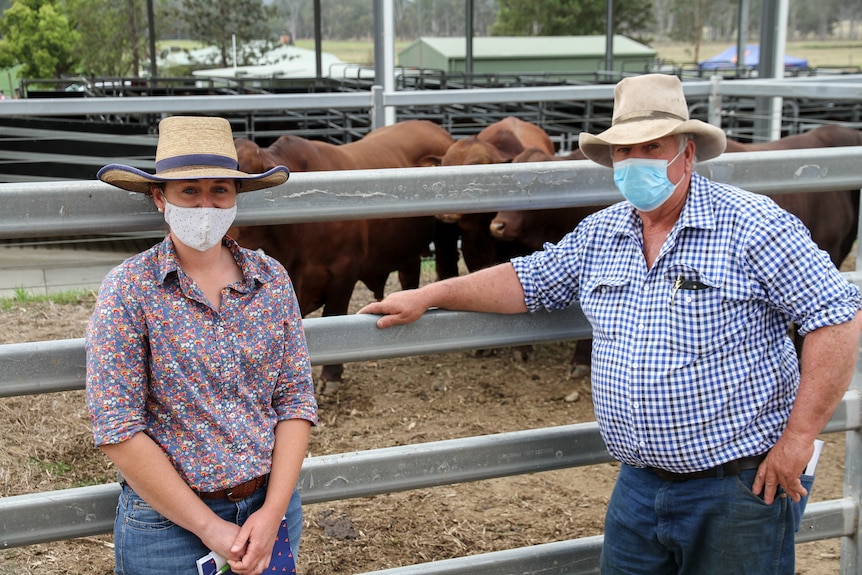 Georgie and Neil Lawrence stand against cattle pens.