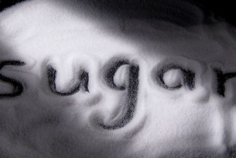 Sugar spread out on a table with the word sugar written in the middle.