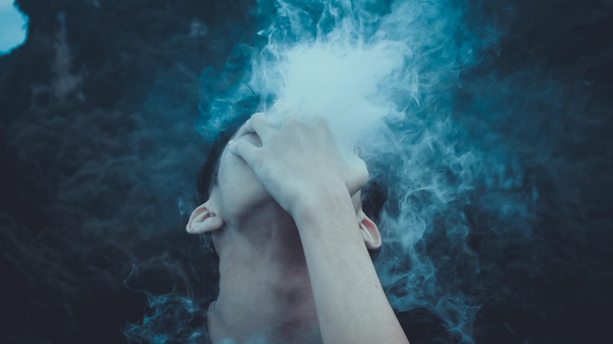 boy looking up to the sky, holding his hand over his face with vapour coming through his fingers
