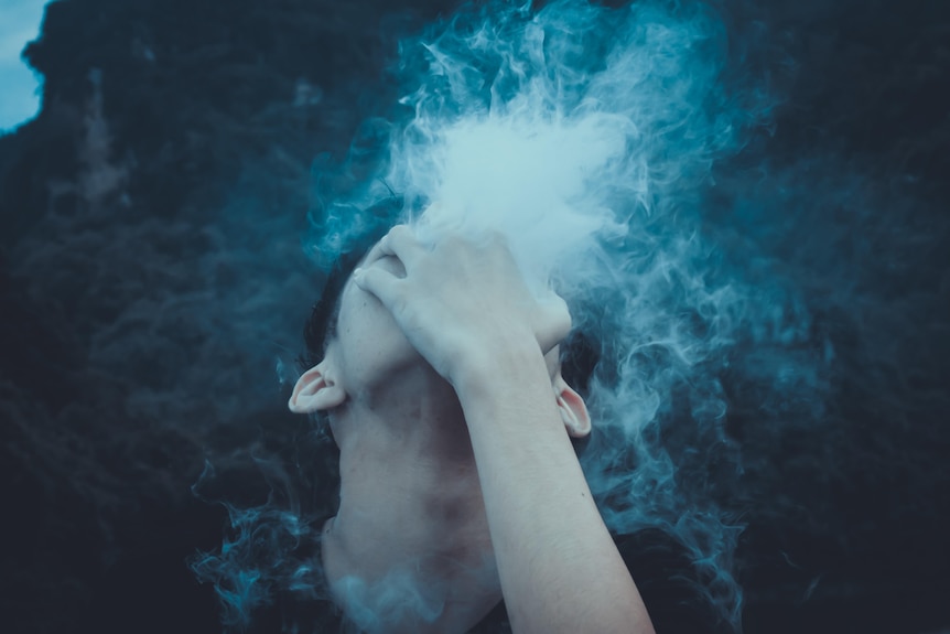 boy looking up to the sky, holding his hand over his face with vapour coming through his fingers