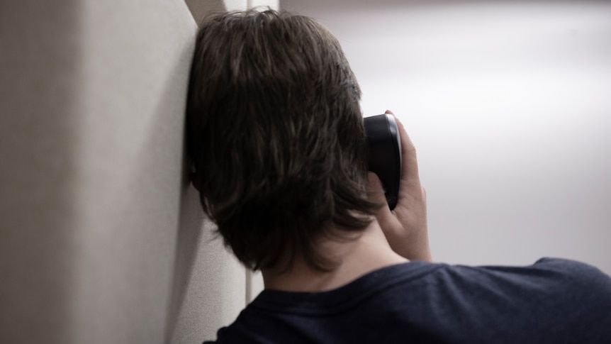 The back of a head of a teenage boy speaking on the phone.