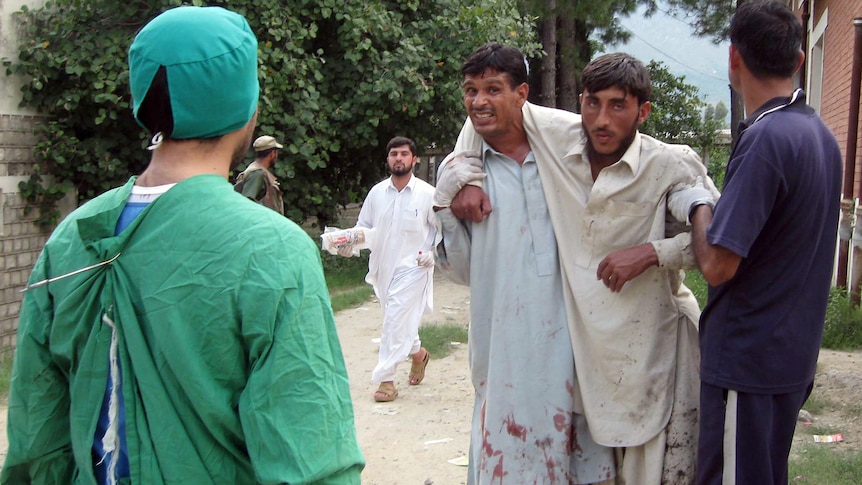 Pakistani paramedics help an injured bomb blast victim