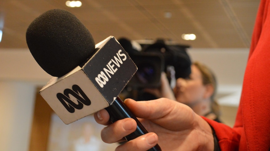 A hand holding a microphone with an ABC News logo.