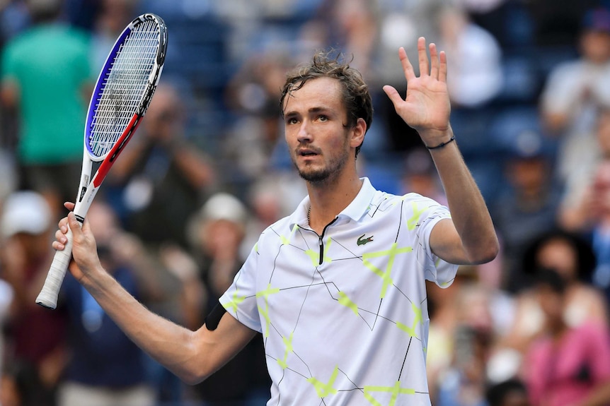 Tennis player raises his racquet and hand to the crowd after winning a match at the US Open.
