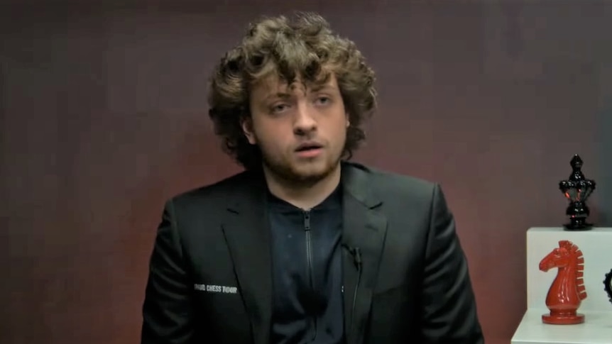 Screenshot of young man in a black jacket talking to camera in an interview