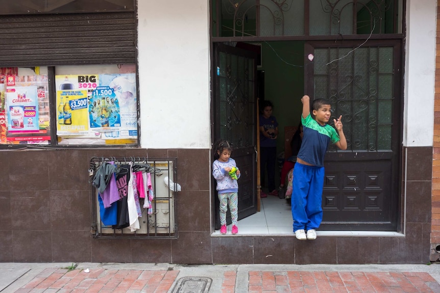 Two children stand at the door to a building