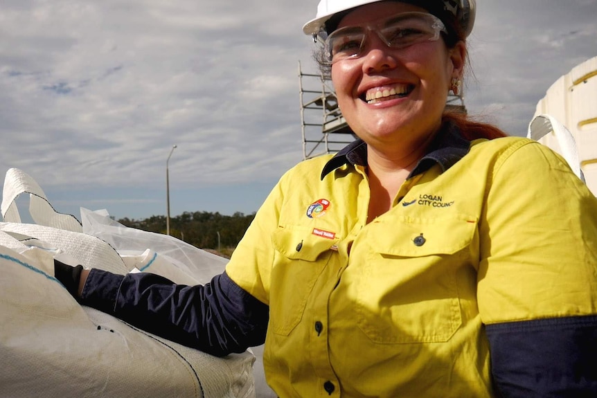 A woman smiling as she stands in an industrial plant