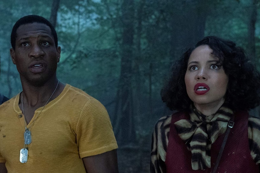 Actors Courtney B. Vance, Jurnee Smollett and Jonathan Majors in a dark forest looing scared in TV show Lovecraft Country