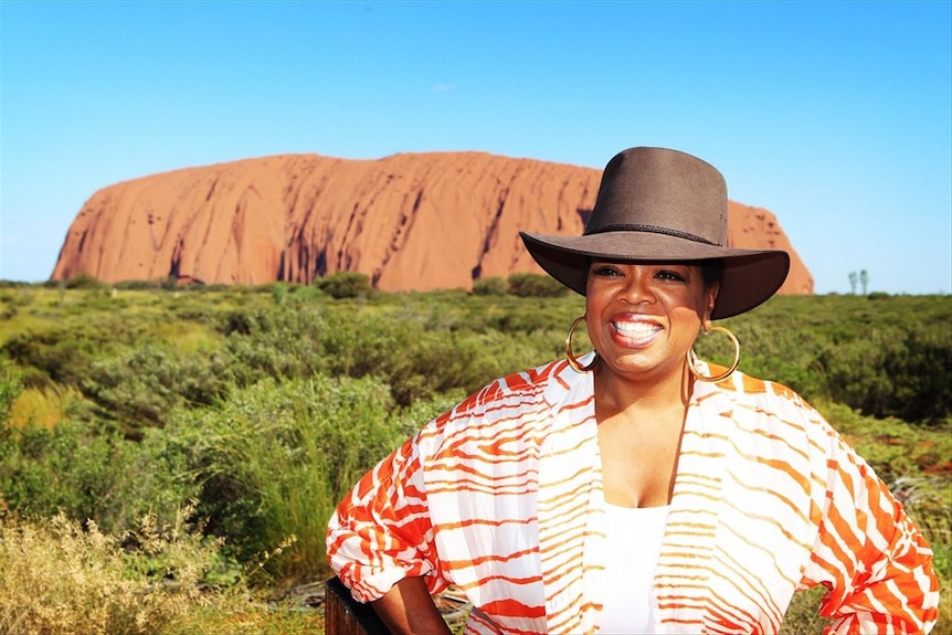 US talk show host Oprah wearing an Akubra hat with Uluru in the background. 