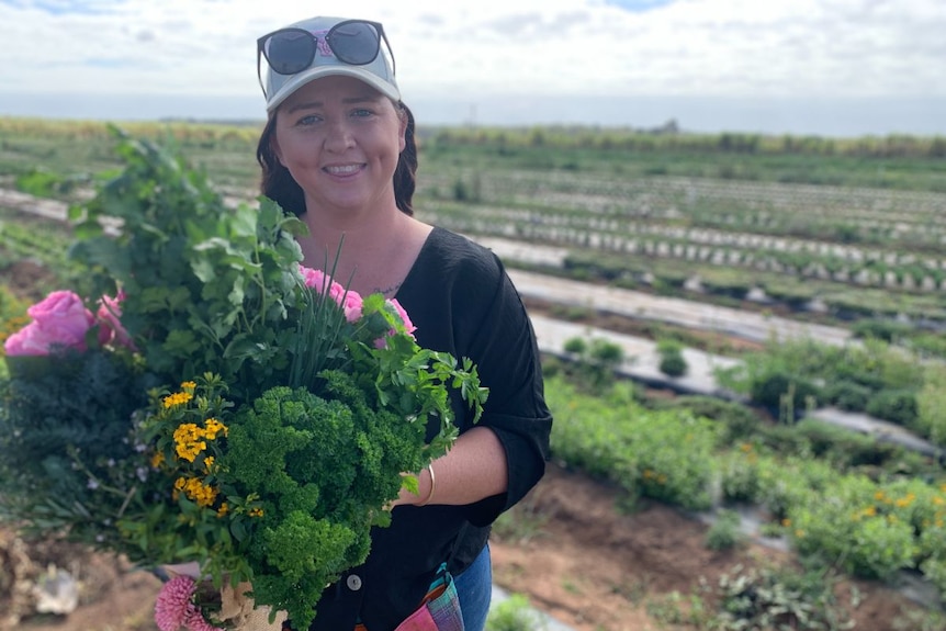 A woman holds a bouquet of herbs and flowers.