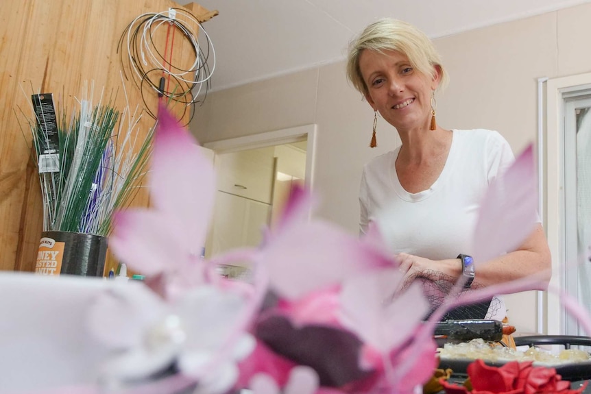 A woman stands in the background with an out of focus pink fascinator in front of her.