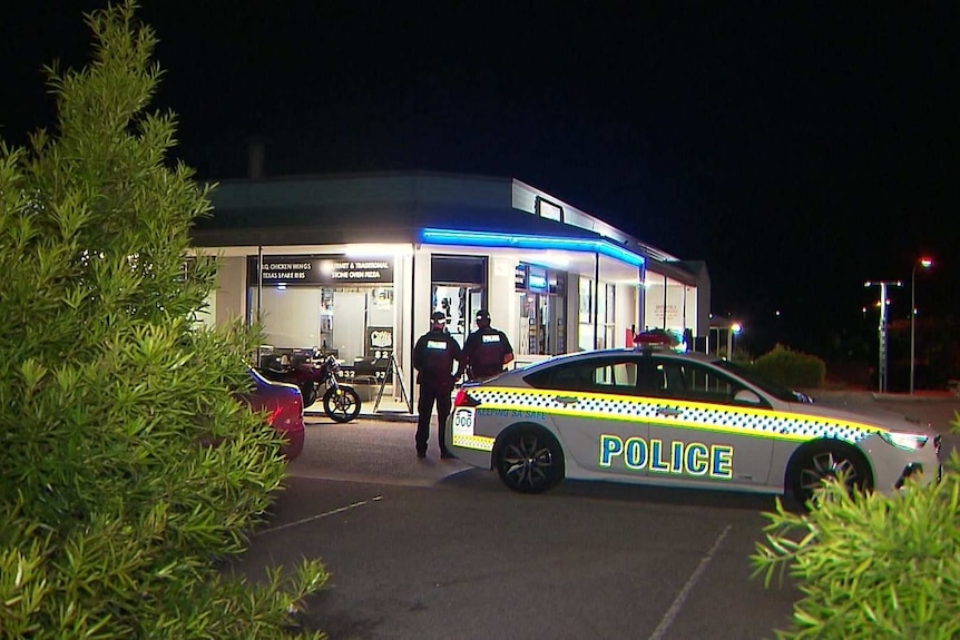 A police car and police officers outside a shop