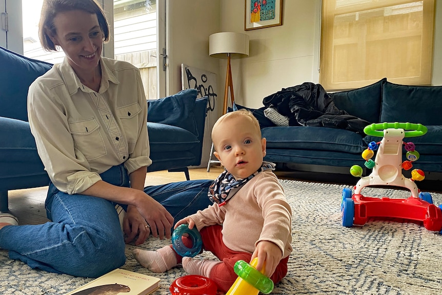 Woman with her baby sitting on the floor playing.