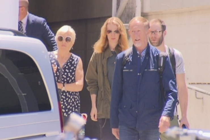 Four people walking towards a car.