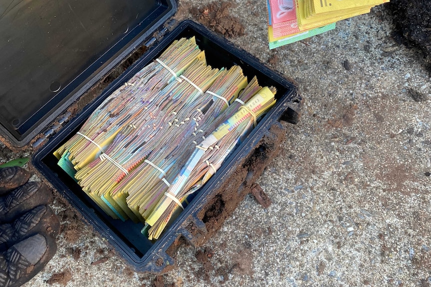 A briefcase full of cash with a bunch of $50 notes being held in front