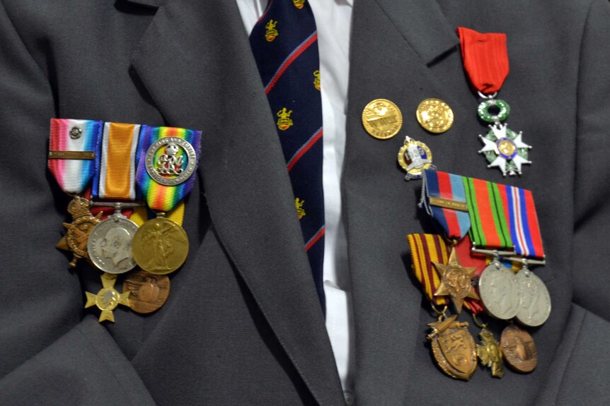 Service medals, including the French Legion of Honour, are seen pinned to a suit.