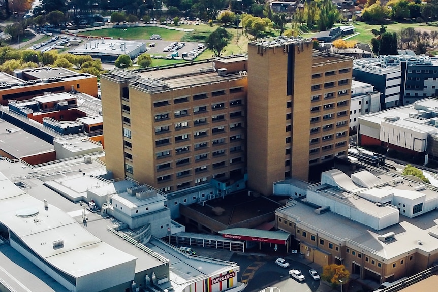 The Canberra Hospital, a multi-storey brick building, is shot from the air.