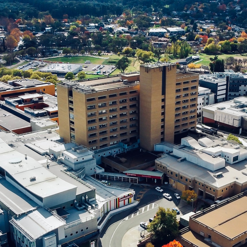 The Canberra Hospital, a multi-storey brick building, is shot from the air.