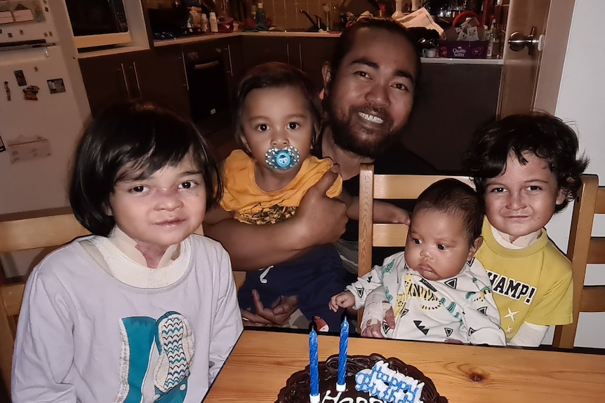 Urodziny Rafiqa, czwórka dzieci i ich ojciec wokół uśmiechniętego ciasta.