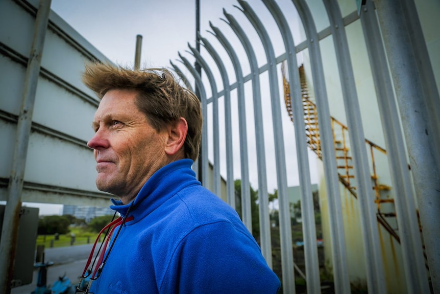 A man standing in front of a fence.