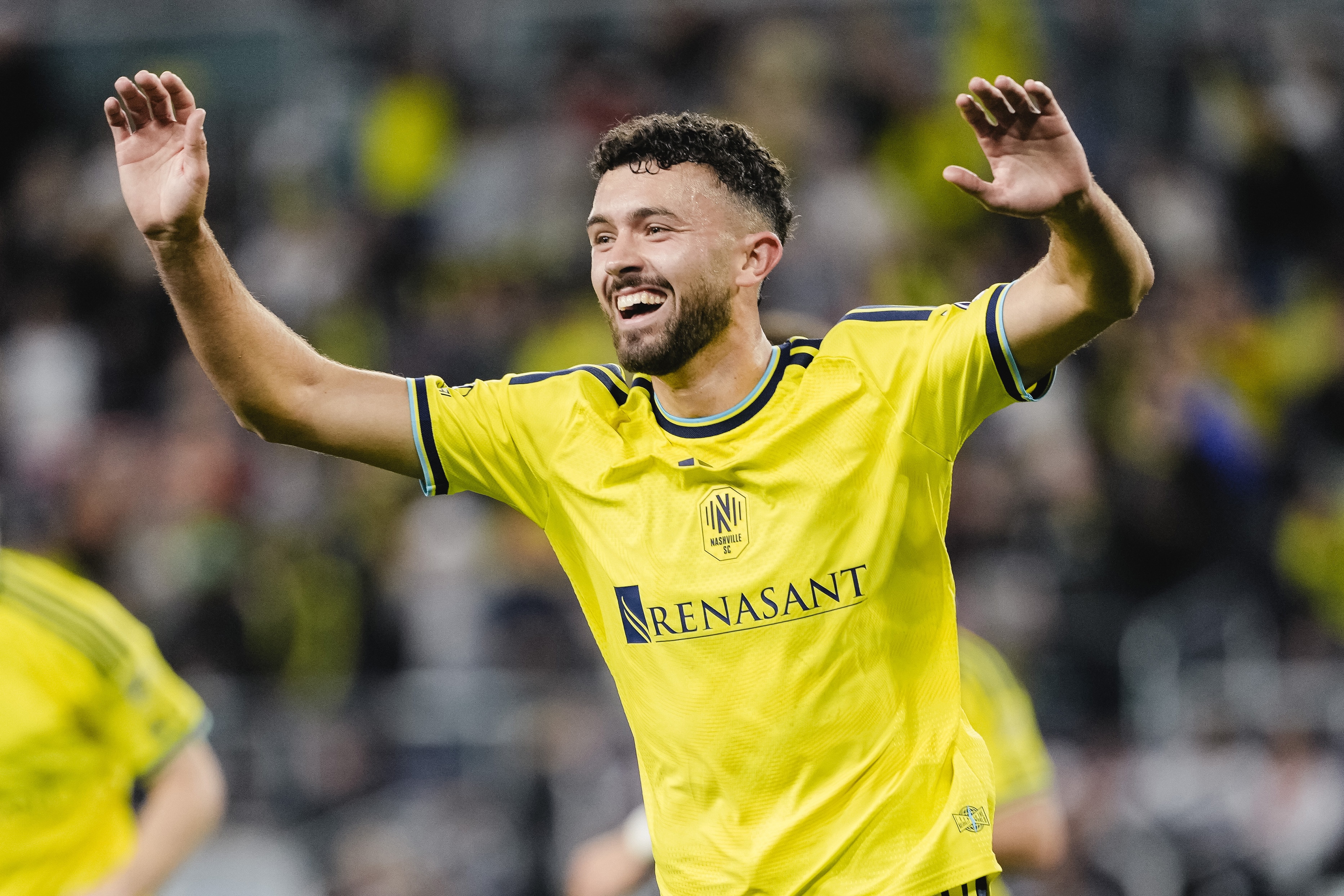 O jogador do Nashville SC, Patrick Yazbek, está com os braços levantados e sorrindo após um gol ser marcado.