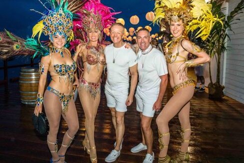 2 men in white surrounded by Brazilian dancers 