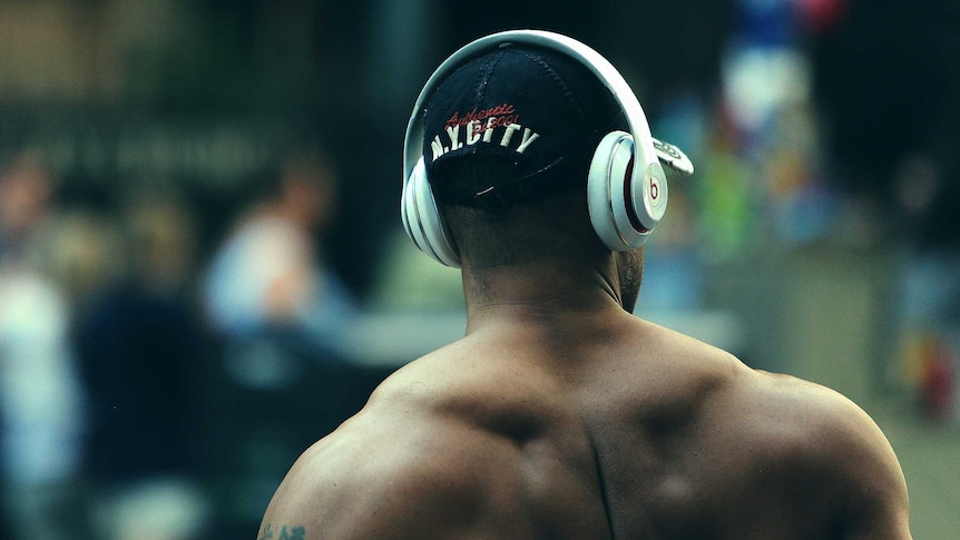 A man with big muscles and no shirt on crossing the road.