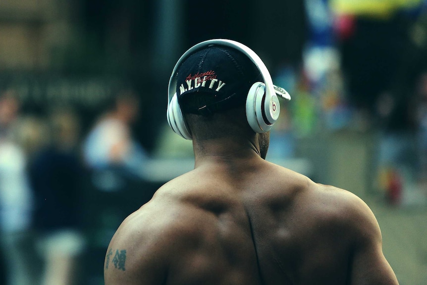 A man with big muscles and no shirt on crossing the road.