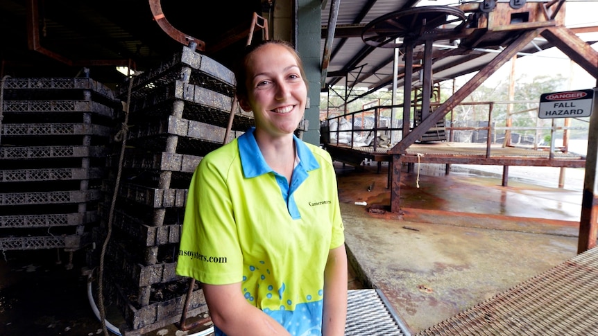 Woman in high vis clothing sits in front of crates.