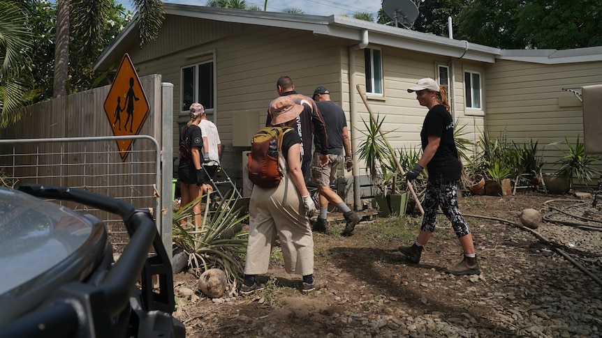 a group of people in boots and gloves walk into a flooded home