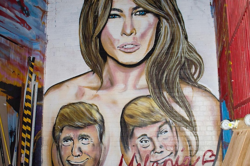 A topless mural of Melania Trump is censored with faces of Donald Trump covering her breasts.