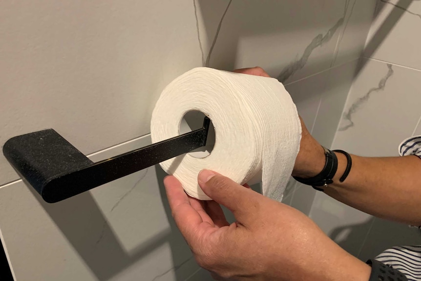 A woman puts toilet paper on to a holder
