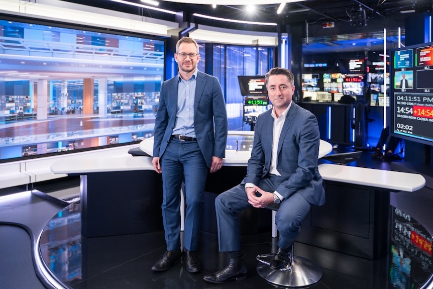 Ayliffe and Morris in studio with TV monitors in background.