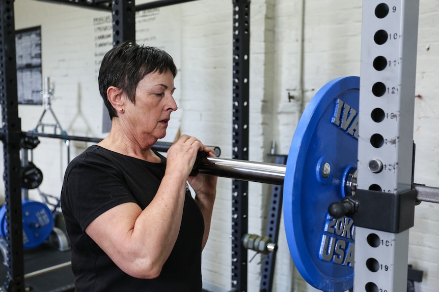 Therese Pollard getting the weights ready in a gymnasium.