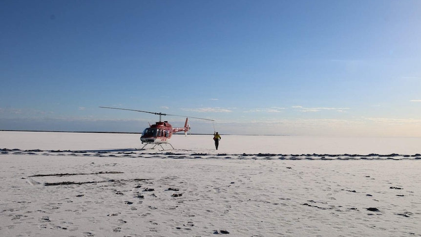 A helicopter on vast white salt lake.