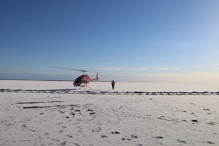 A helicopter on vast white salt lake.