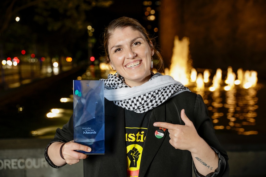 A woman smiling at the camera holding an award