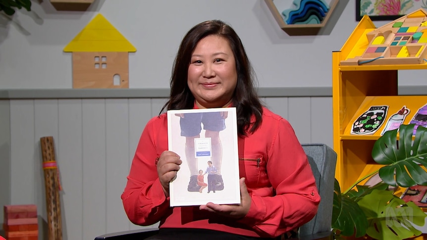 Teacher Ada Chan holds up story book, My Strange Shrinking Parents