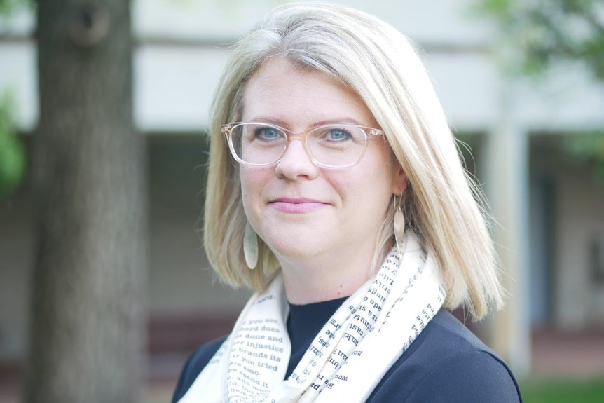 A woman wearing glasses standing outside.