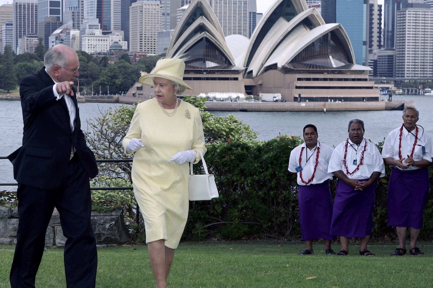 Queen Elizabeth II and John Howard walk on the lawns of Admiralty House, with the Sydney Opera House in the background.